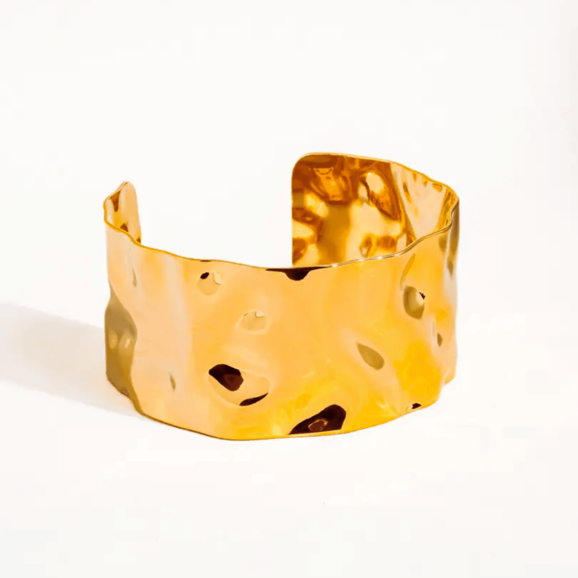 Gold cuff bracelet with textured surface on a white background